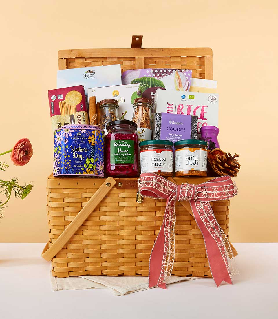 Luxury gourmet gift hamper with jars of pickled vegetables, kimchi, and specialty foods in woven wicker basket with red