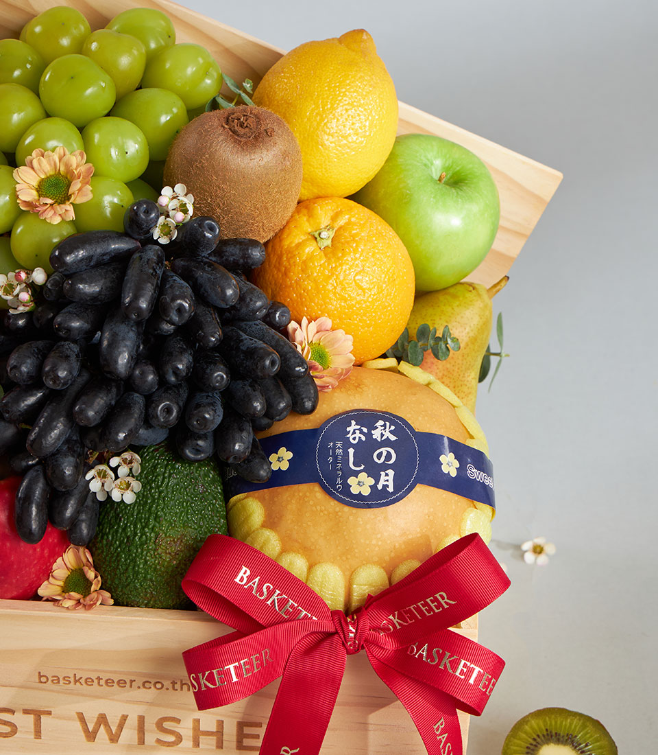 Premium wooden fruit crate with assorted fresh fruits, green grapes, kiwi, lemon, and pear, tied with red ribbon bow