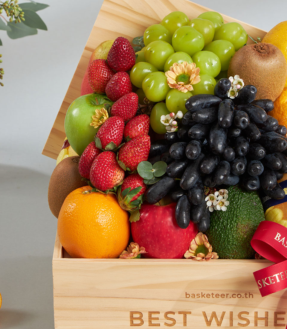 Premium wooden crate with assorted fresh fruits, grapes, apples, berries, and decorative flowers