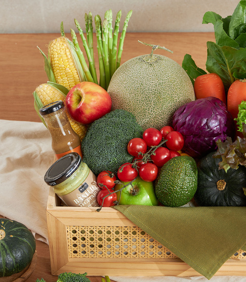 Wooden crate filled with fresh organic vegetables, corn, asparagus, cantaloupe, apples, broccoli, tomatoes and artisan
