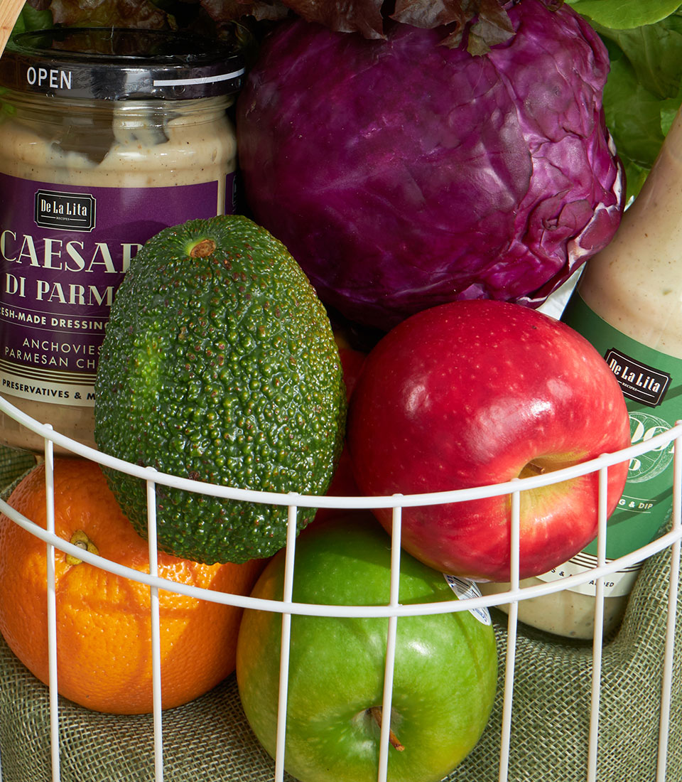Fresh green wellness vegetable basket with avocado, apples, cabbage and artisan dressings