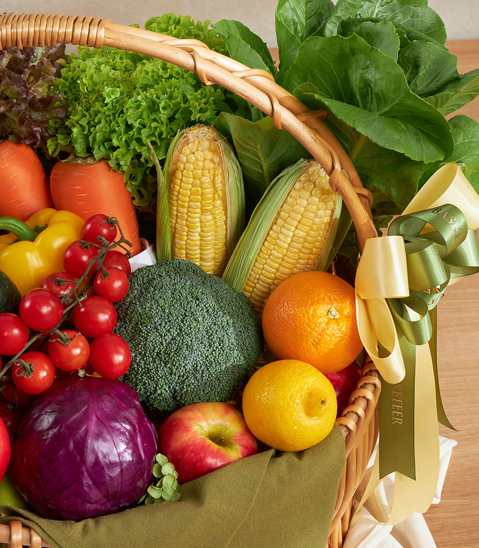 Luxury vegetable and fruit hamper with fresh corn, broccoli, bell peppers, and seasonal produce in wicker basket with gold