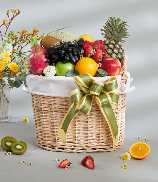 Premium tropical and imported fruit gift basket with pineapple, apples, grapes, dragon fruit, and citrus in woven wicker