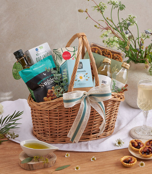 Premium gourmet gift basket with olive oil, healthy snacks, sparkling drinks and artisan chocolates in woven wicker