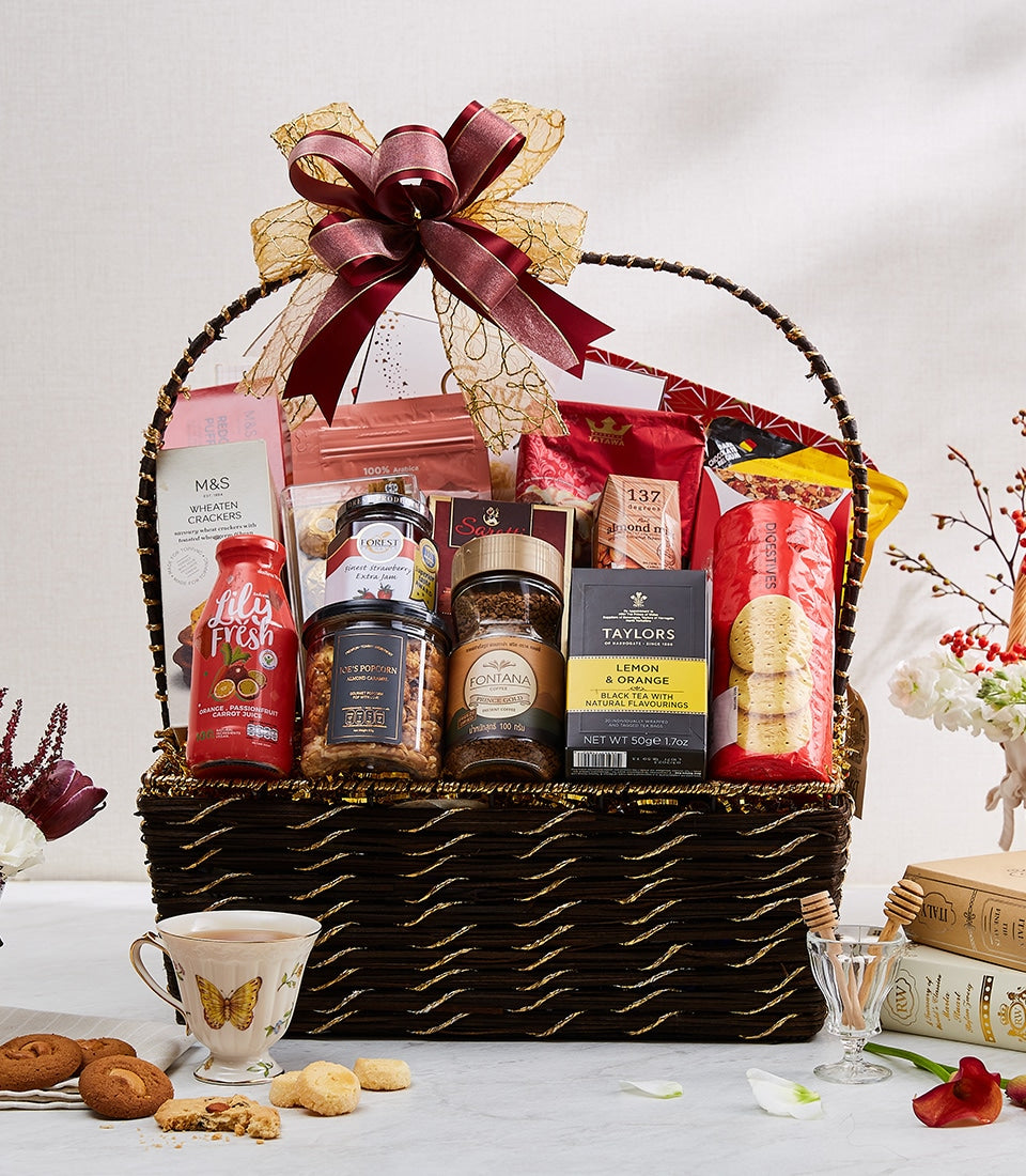 Dark brown wicker gift basket filled with gourmet imports, red and gold ribbon bow, perfect for New Year celebrations