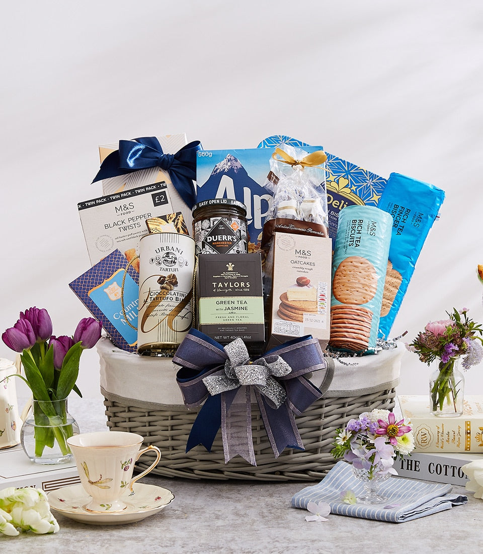 Luxury gourmet gift basket with dark blue ribbon, grey wicker design, filled with international delicacies and tea for New