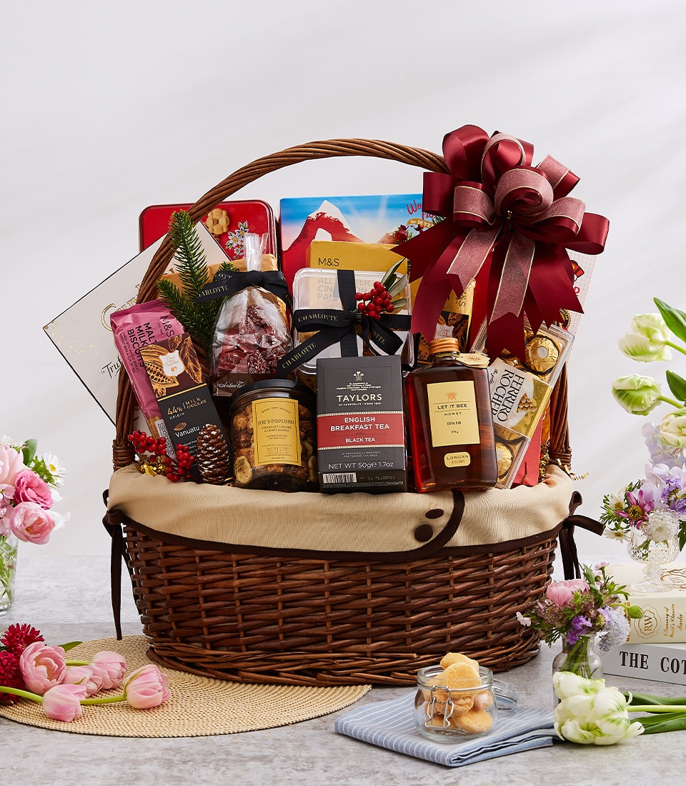 Luxury gourmet gift basket with imported chocolates, tea, and fine foods, finished with deep red ribbon for New Year gifting