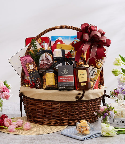 Luxury gourmet gift basket with imported chocolates, tea, and fine foods, finished with deep red ribbon for New Year gifting