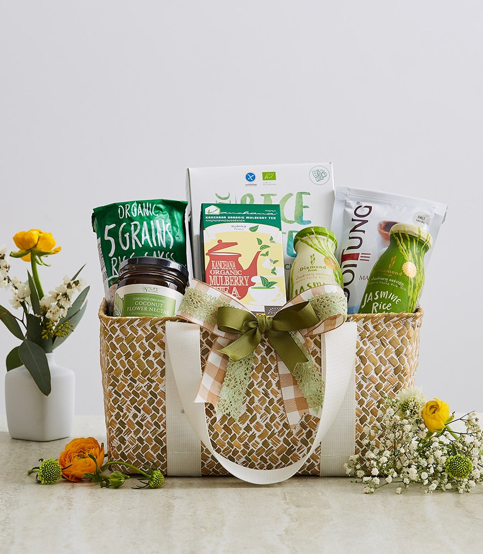 Woven natural fiber gift basket with organic grains, coconut nectar, mulberry tea, and jasmine rice, accented with gingham