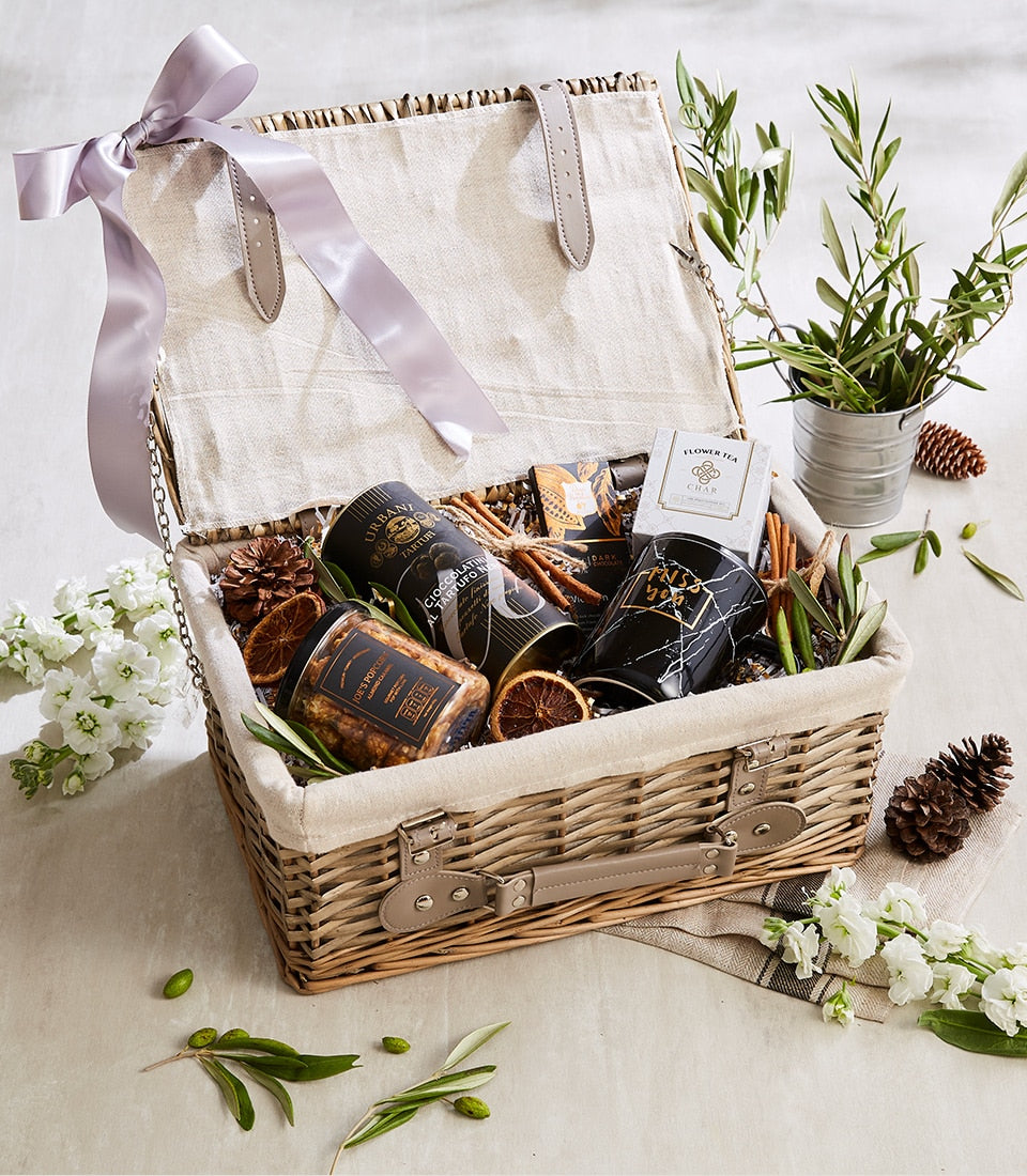 Nourish & Nosh gourmet gift hamper in wicker basket with truffle chocolates, popcorn, flower tea, and marble mug