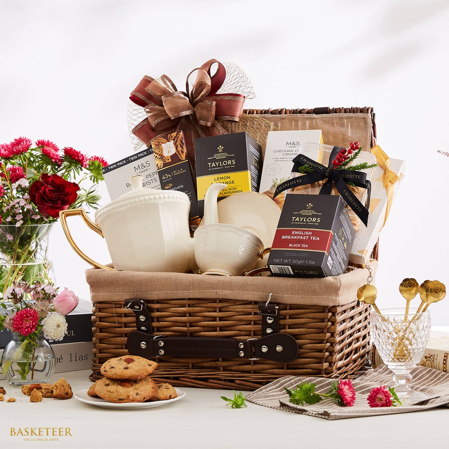 Premium wicker hamper filled with gourmet tea, cheese crisps, ceramic teapot, fresh red roses and artisan cookies