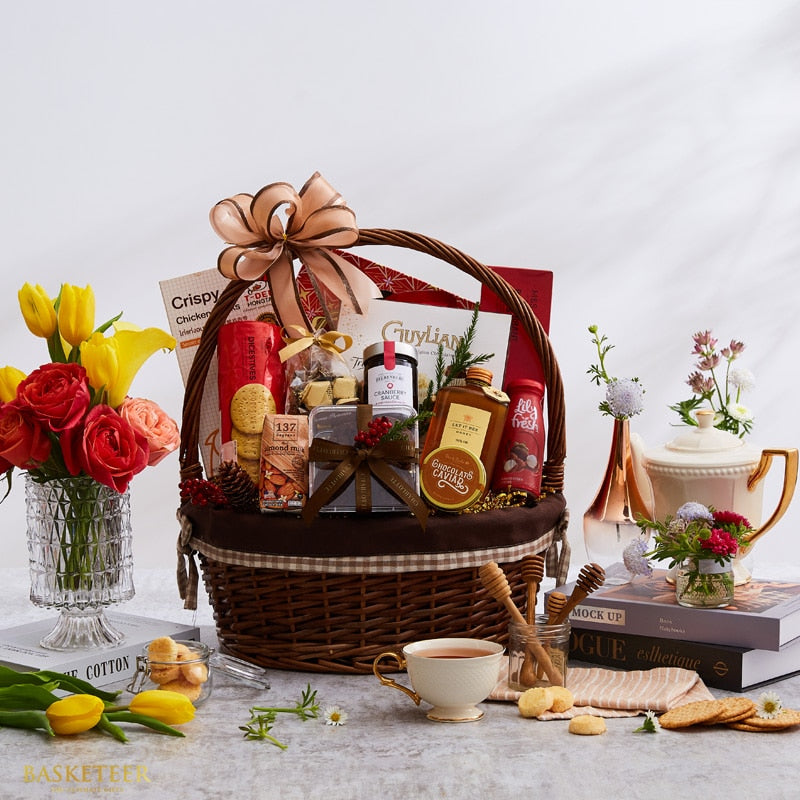 Luxury dark brown wicker gift basket with gourmet foods, satin bow, and festive styling with roses and tulips