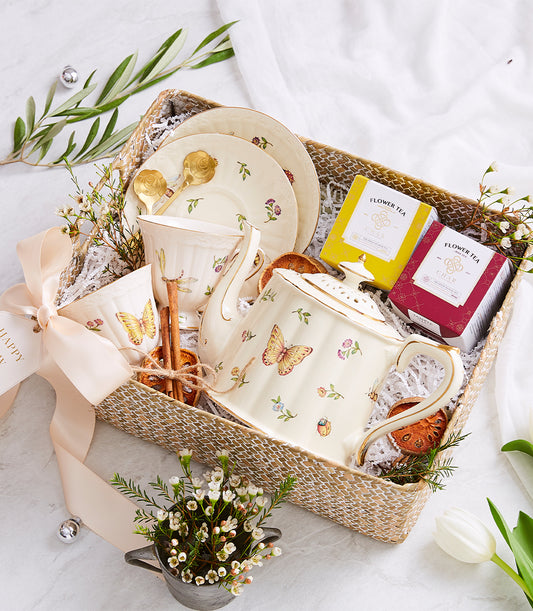 Basketeer premium hamper delivery Thailand: Teapot, cups, saucers, and flower tea in a woven gift box. Tied with a peach ribbon. A luxury gift basket Bangkok.