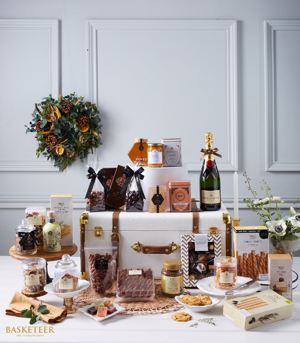 Luxury champagne and gourmet gift hamper with chocolates, preserves, and artisan treats in leather trunk