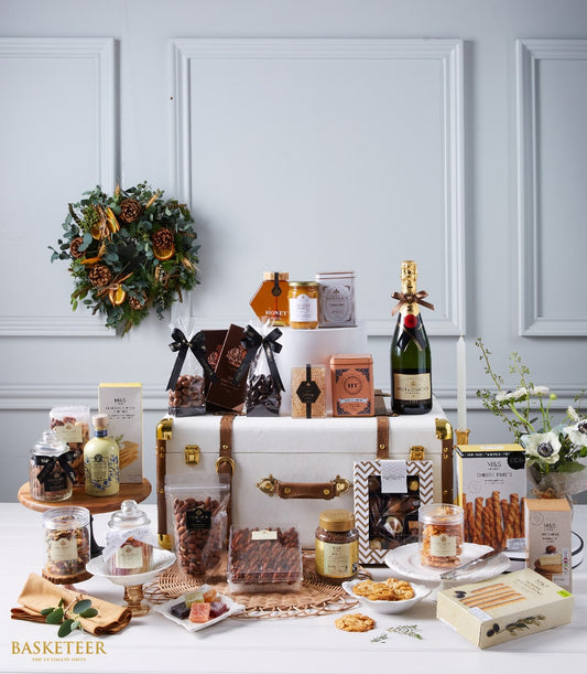 Luxury champagne and gourmet gift hamper with chocolates, preserves, and artisan treats in leather trunk