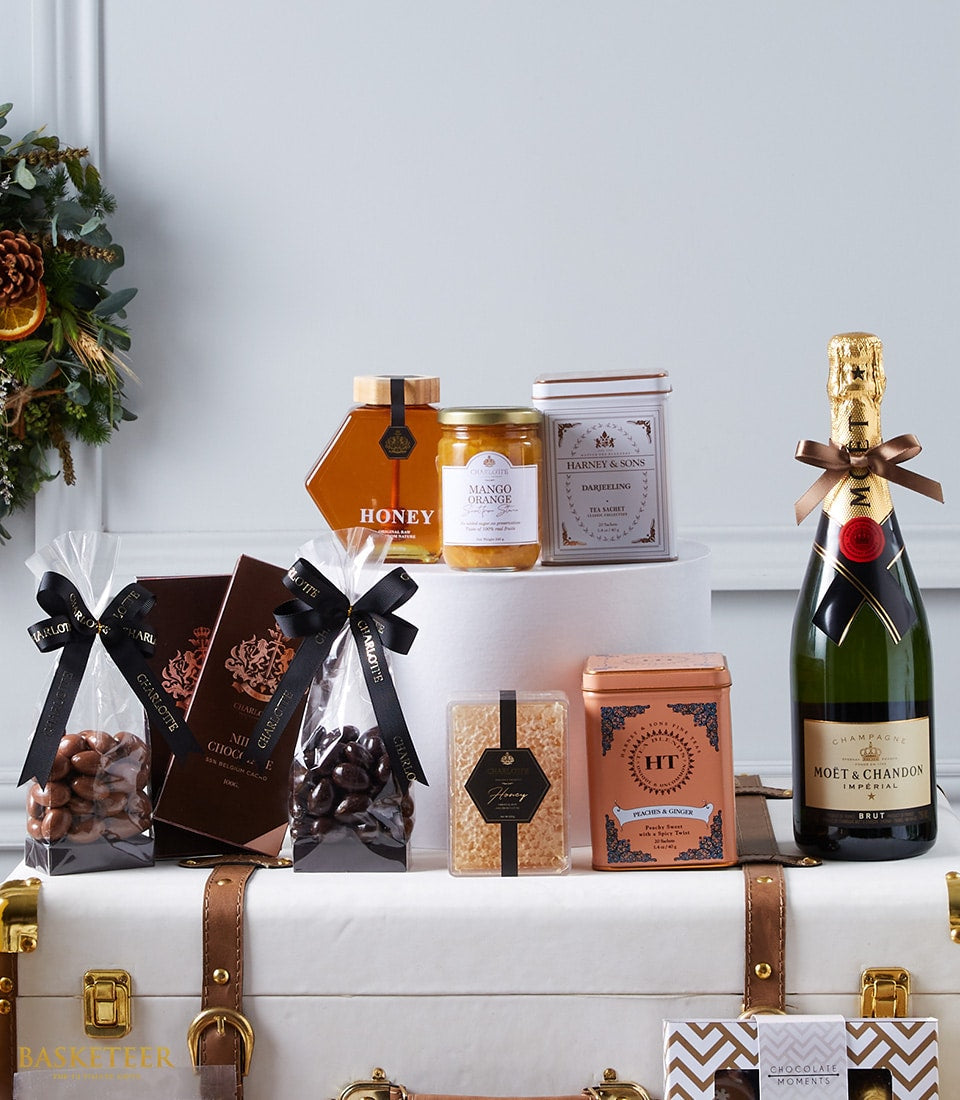 Luxury champagne gift hamper with honey, preserves, tea, chocolates, and honeycomb on white display
