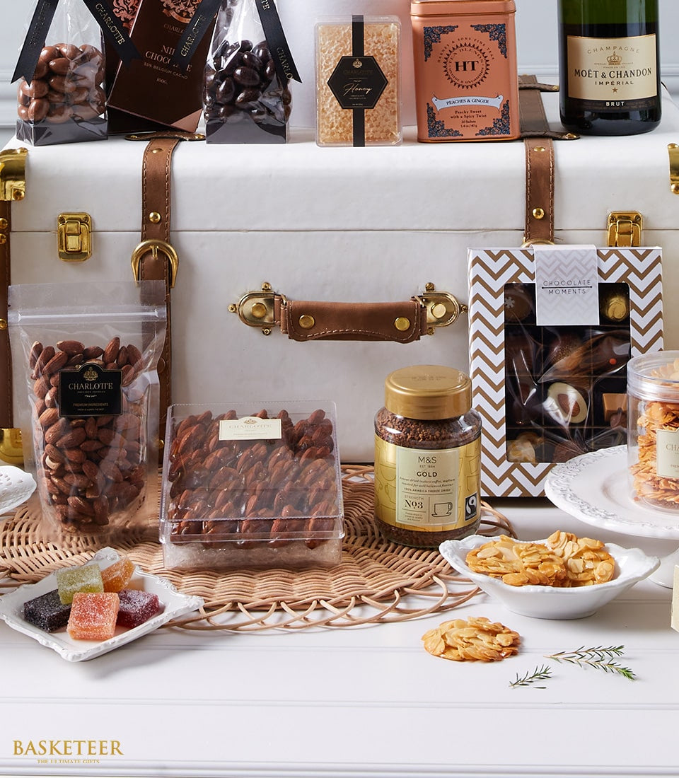 Luxury champagne gift hamper in white leather trunk with gourmet chocolates, nuts, and artisan treats