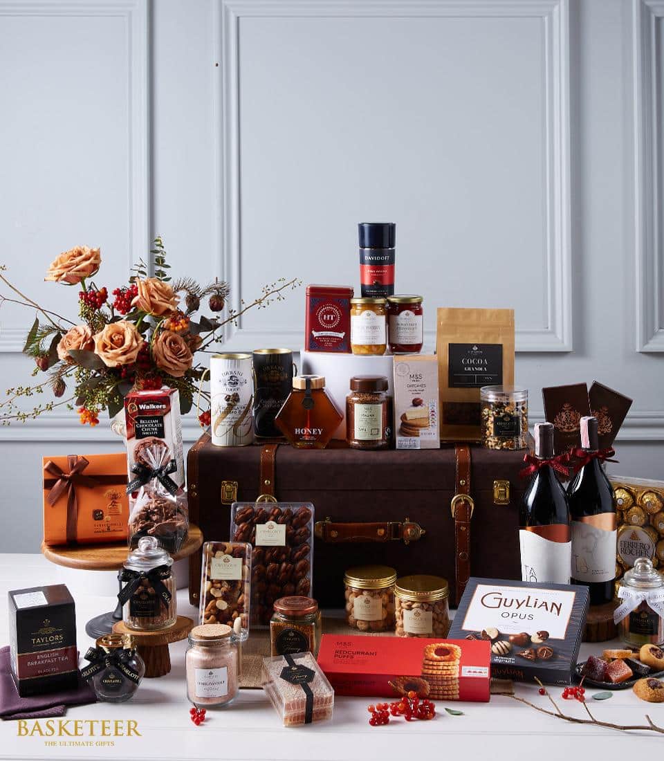 Deluxe leather trunk wine hamper with red wines, gourmet chocolates, honey, and orange rose arrangement