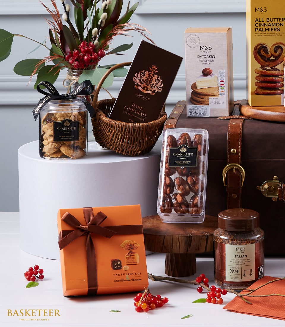 Luxury gourmet hamper with chocolates, cookies, dates, coffee, and oatcakes in elegant brown and gold packaging