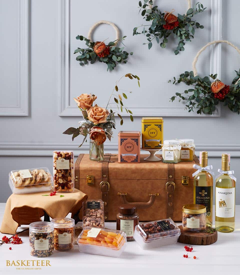 Luxury wine hamper with white wines, gourmet tea, nuts, dried fruit, cookies, and peach roses in brown leather trunk