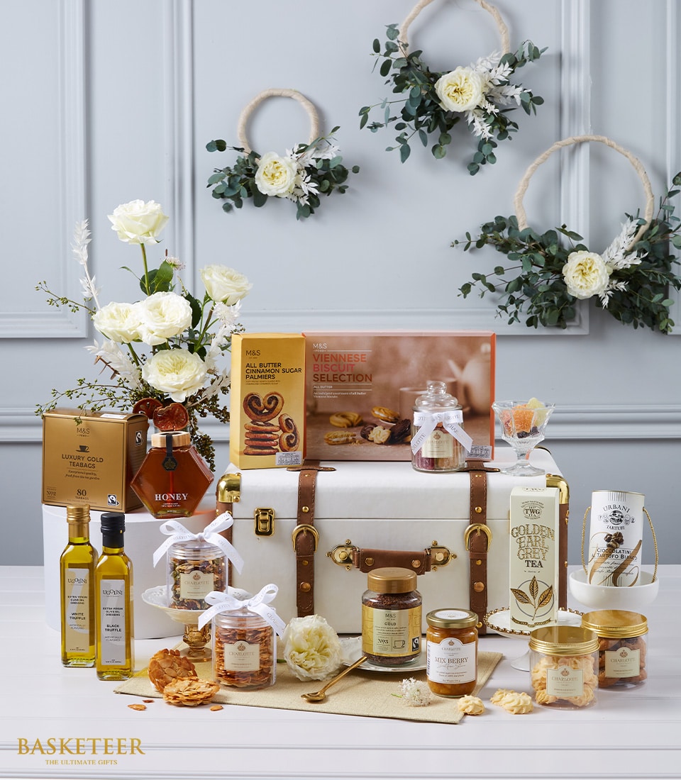 Luxurious gourmet hamper with white trunk, premium biscuits, truffle oils, honey, specialty teas, and fresh white roses