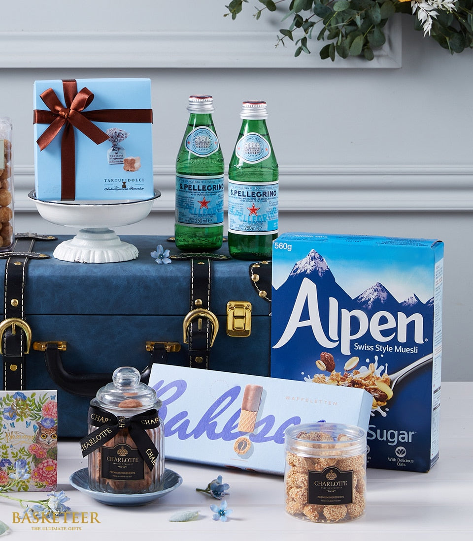 Sumptuous Global Elegance luxury gift hamper with gourmet foods, sparkling water, and artisan treats on blue trunk