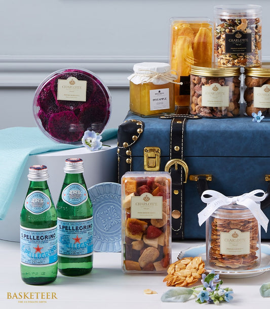Luxury gourmet gift hamper with sparkling water, dried fruits, nuts, and artisan preserves in dark blue leather trunk with