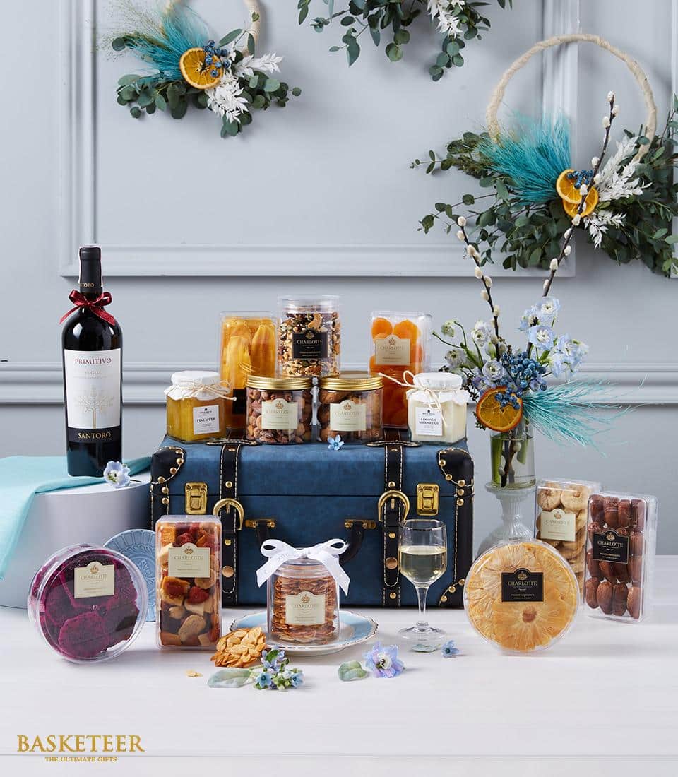 Luxury wine and gourmet hamper with red wine, nuts, dried fruits and honey on blue vintage trunk