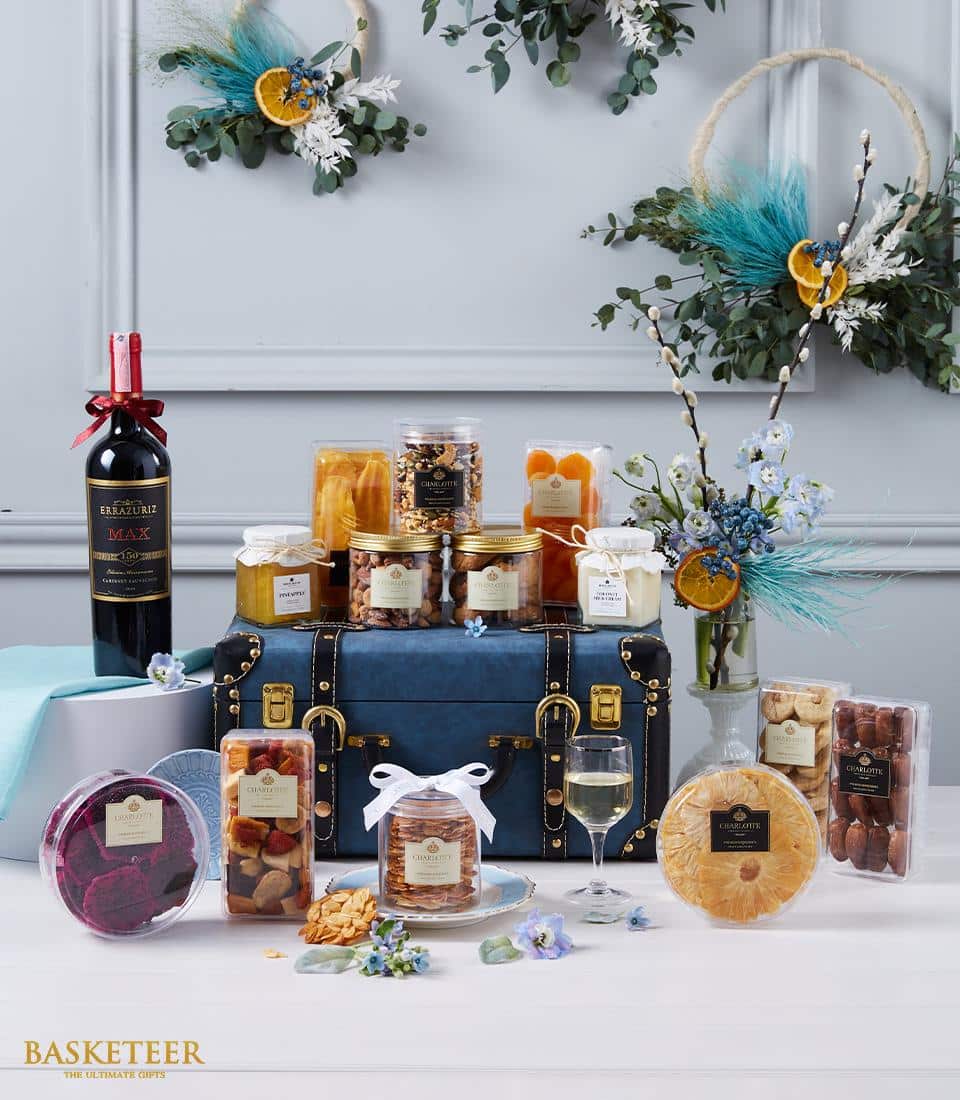 Luxury wine and gourmet hamper with red wine, nuts, dried fruits, and artisan preserves in leather trunk display