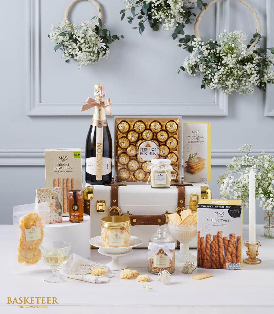 Luxury hamper with champagne, gourmet chocolates, cheese crisps, and artisan treats in white trunk with gold accents