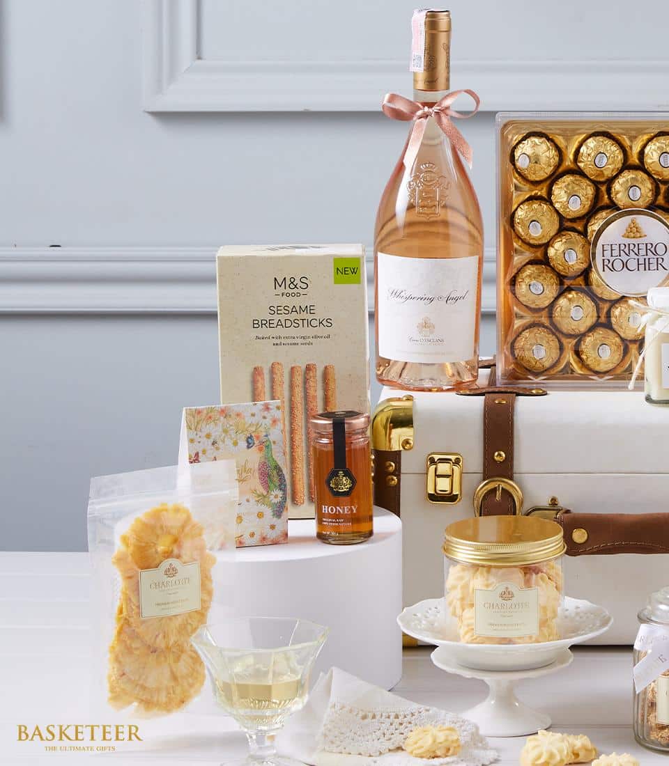 Luxury rosé wine hamper with Ferrero Rocher chocolates, honey, breadsticks, and artisan treats in white trunk-style gift box