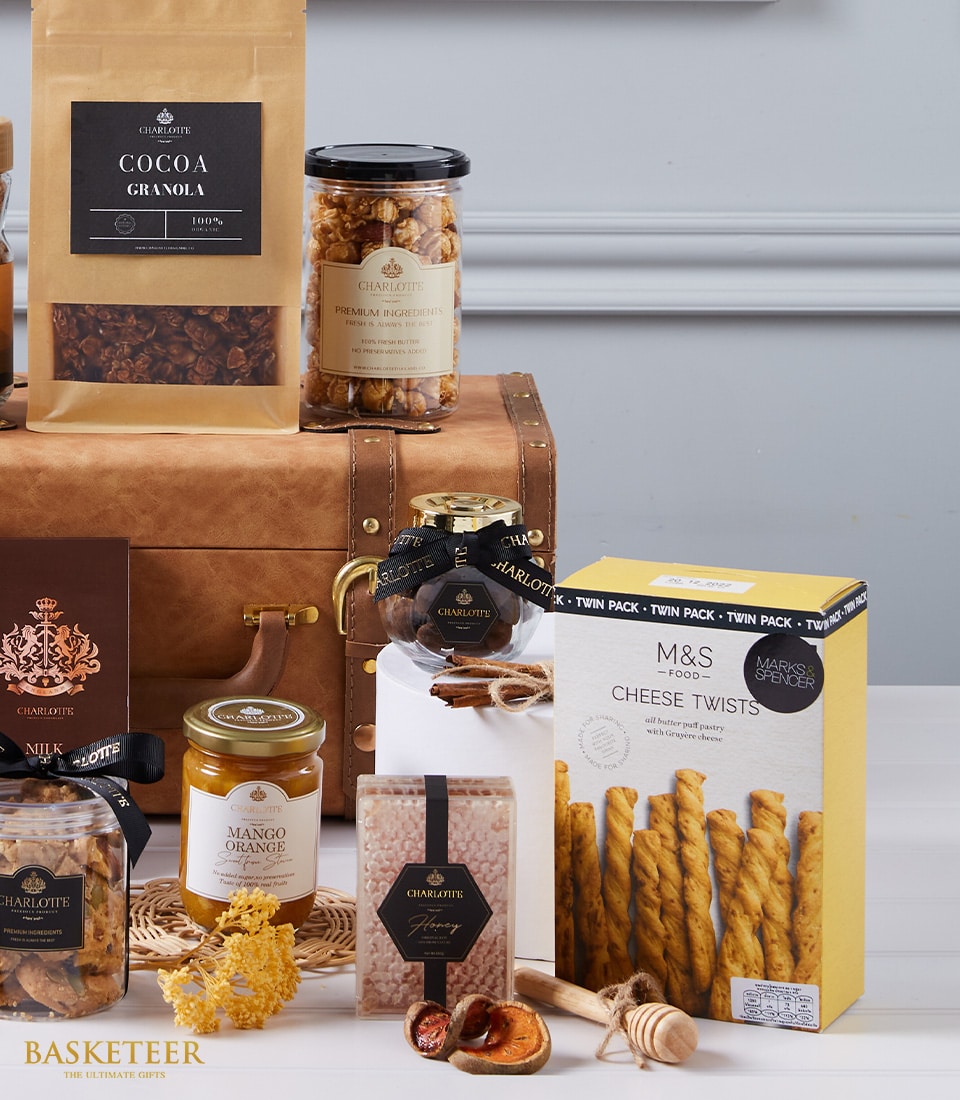 Luxury gourmet hamper with imported chocolates, jams, granola, and artisan treats arranged on leather trunk