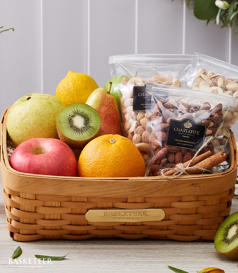 Woven wooden basket filled with fresh pears, apples, oranges, and kiwis alongside premium cashews, almonds, and pistachios