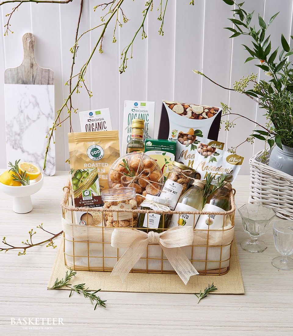 Premium wellness gift basket with organic coffee, nuts, and citrus in gold wire basket with cream ribbon
