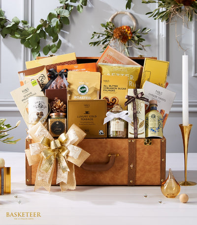 Luxury leather trunk gift hamper overflowing with gourmet chocolates, tea, coffee, and artisan treats with gold ribbon bow