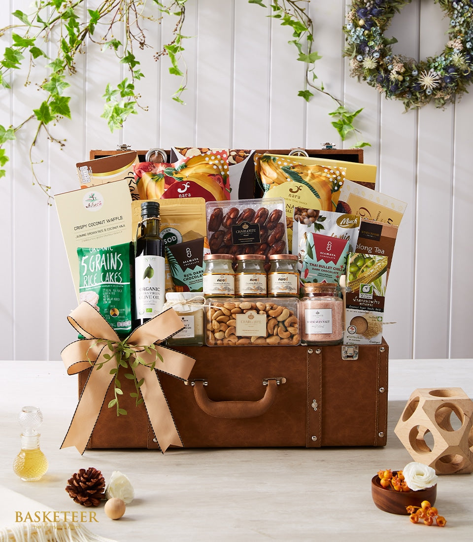 Luxury gourmet gift hamper in brown leather suitcase box with organic rice cakes, dates, cashews, olive oil, chocolate, and