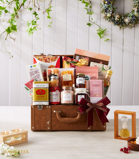 Luxury worldwide gourmet hamper in vintage brown suitcase with organic foods, honey, olive oil and red ribbon bow