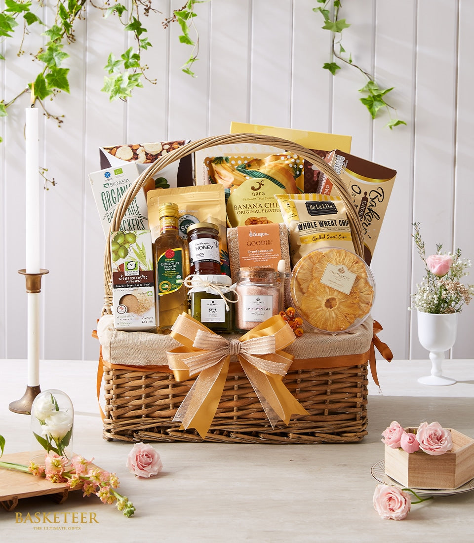 Woven wicker gift basket with gourmet Thai wellness foods, honey, coconut vinegar, and organic crackers tied with gold
