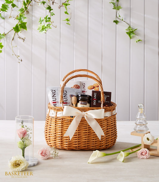 Doi Tung gourmet gift basket with honey, cookies, and premium artisan goods, styled with fresh roses and white flowers