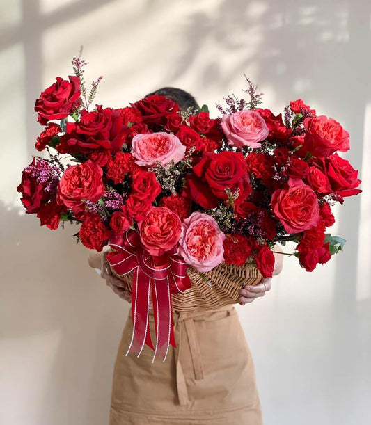 Scarlet and blush roses in wicker basket with red satin bow, premium fresh flower arrangement for get well wishes