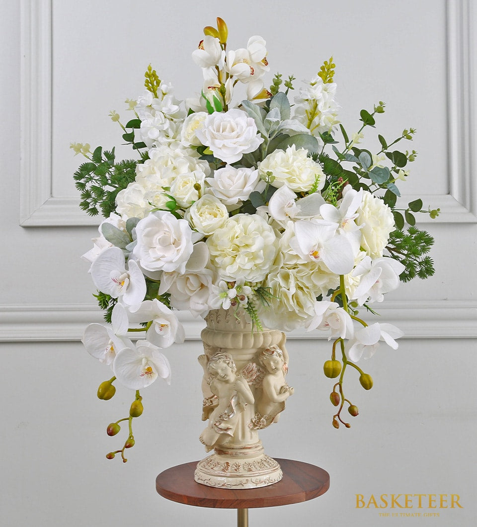 Elegant white artificial flower arrangement with roses and peonies in ornate cream pedestal vase
