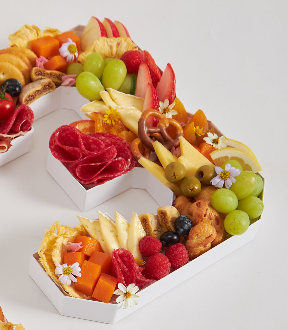 Number 3 shaped charcuterie and fruit board with cheese, cured meats, grapes, berries, and crackers for birthday celebrations