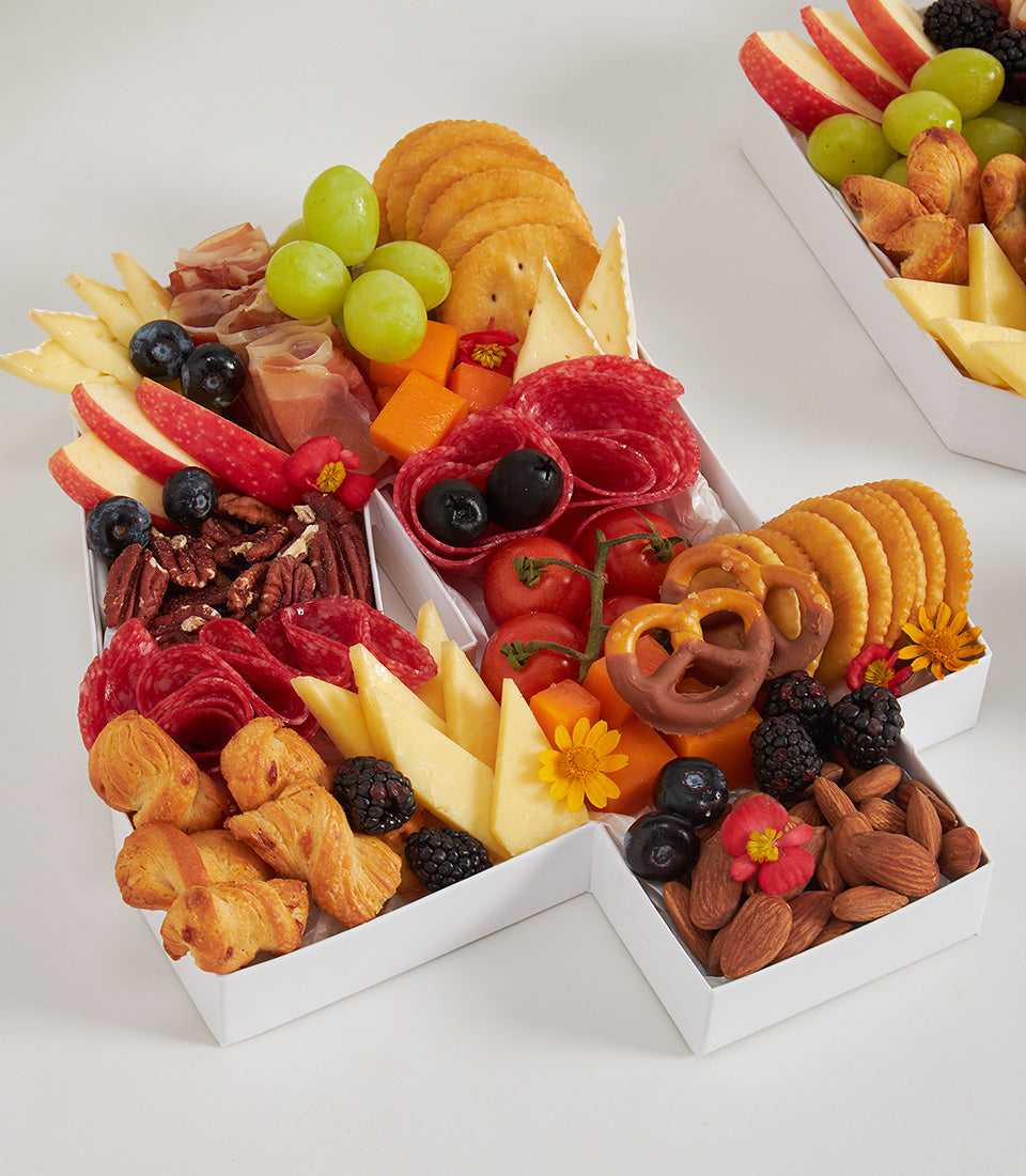 Number 1 charcuterie board with fresh fruits, artisan cheeses, cured meats, and edible flowers in white segmented tray