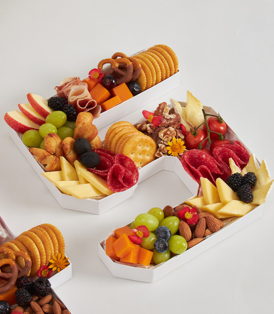 Charcuterie number box with fresh fruits, cheeses, cured meats, and pastries arranged in letter shapes for birthday
