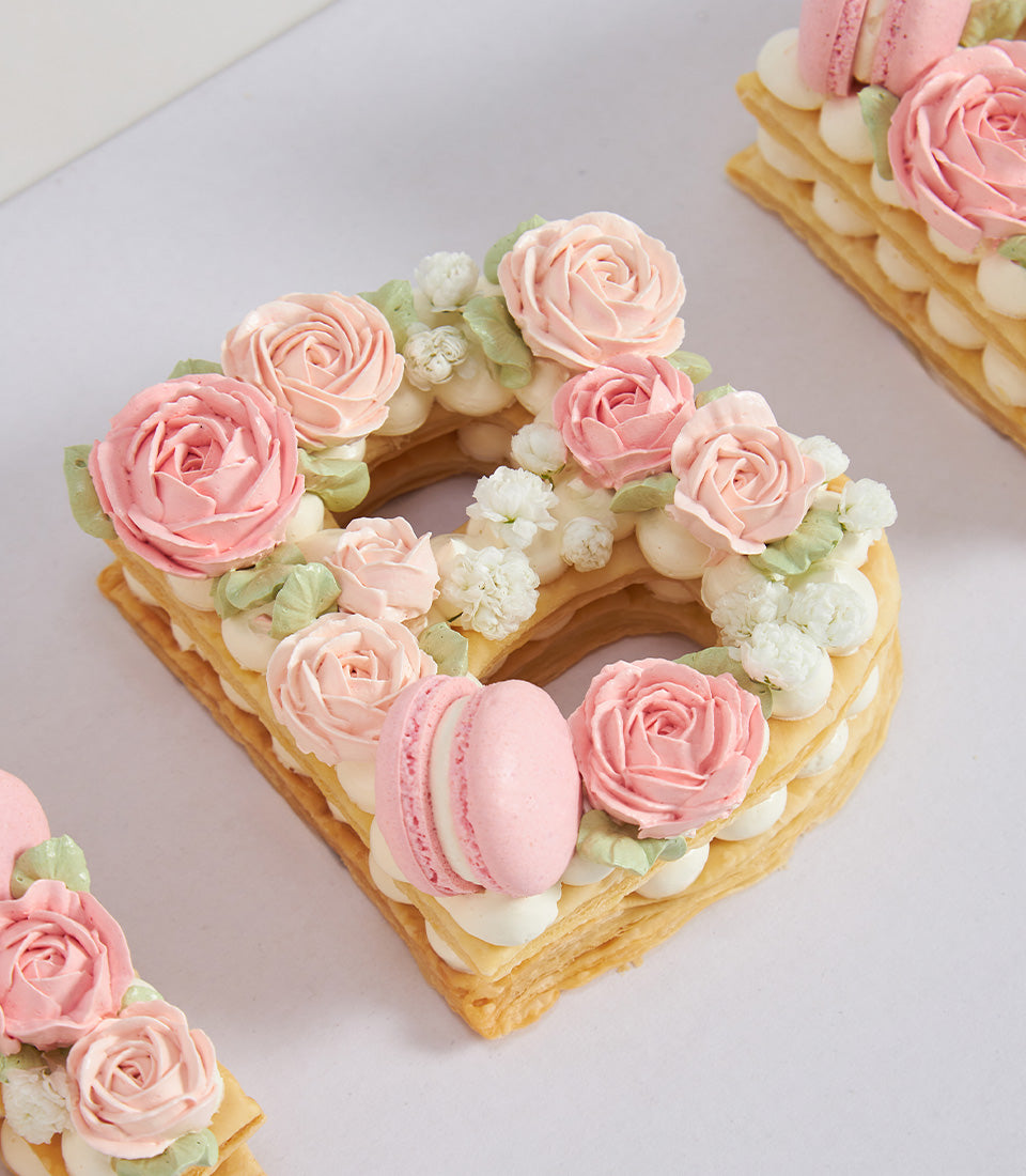 Birthday letter cake "B" with pink buttercream roses, cream filling, and macaron accent
