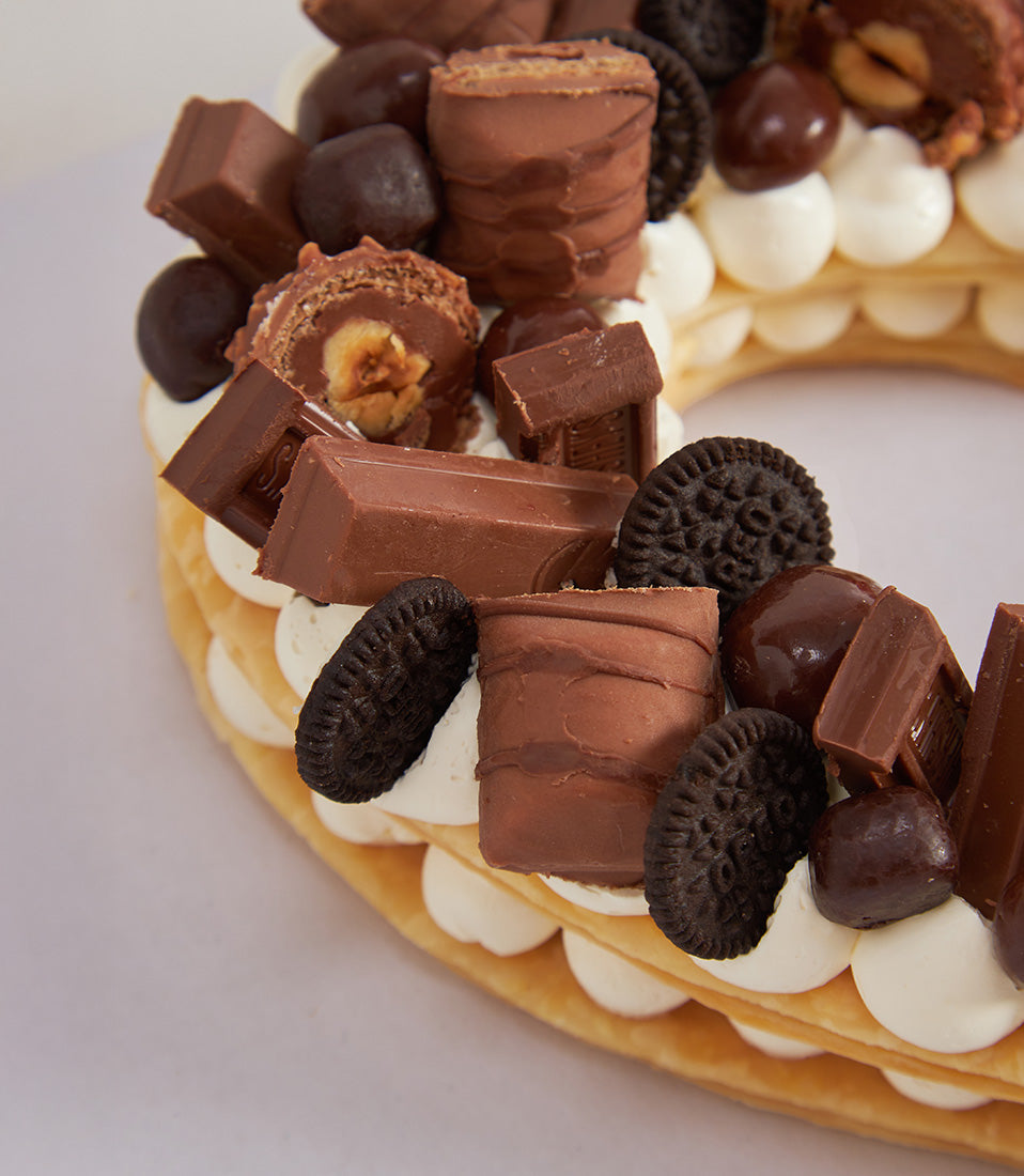 Heart-shaped chocolate and strawberry celebration cake with candy and cookie toppings