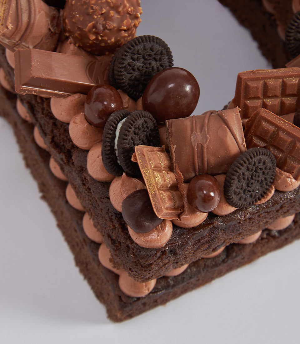 Decadent chocolate letter cake topped with Oreos, chocolate bars, and candy clusters