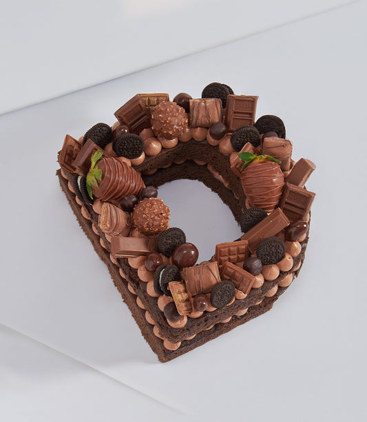Heart-shaped chocolate layer cake topped with Hershey's bars, truffles, Oreos and chocolate-covered strawberries