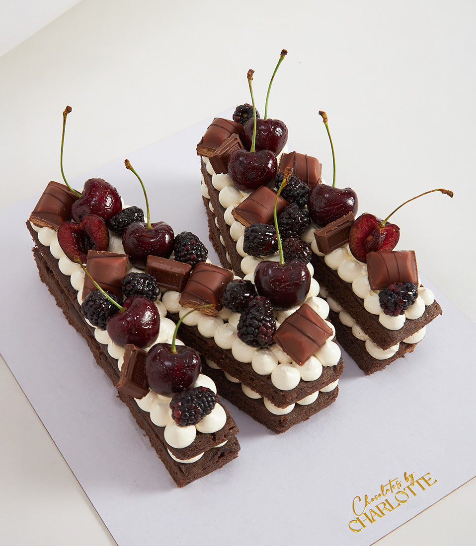 Chocolate cherry bliss letter cakes with dark chocolate layers, white cream frosting, fresh cherries and blackberries