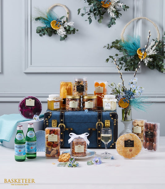 Luxury gourmet hamper with dried fruits, nuts, preserves, and sparkling water on vintage blue trunk